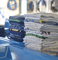 a stack of folded shirts sitting on top of a blue table