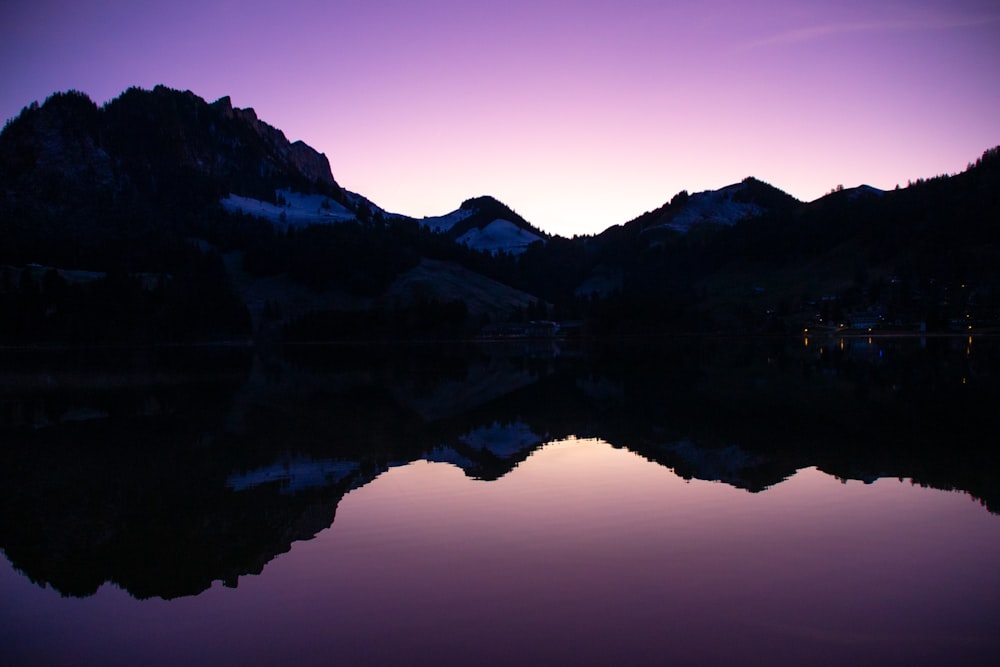 a mountain range is reflected in the still water of a lake