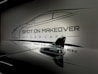 A sleek and glossy surface reflecting a stylized design of a car with the words 'Spot On Makeover Car Care' in a minimalistic and modern font. The image includes a focus on a small shark-fin antenna, emphasizing a clean and sophisticated automotive theme.