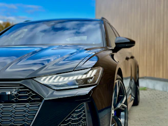 A sleek black car parked in front of carro.com's modern dealership in Cabo Frio under a clear blue sky.