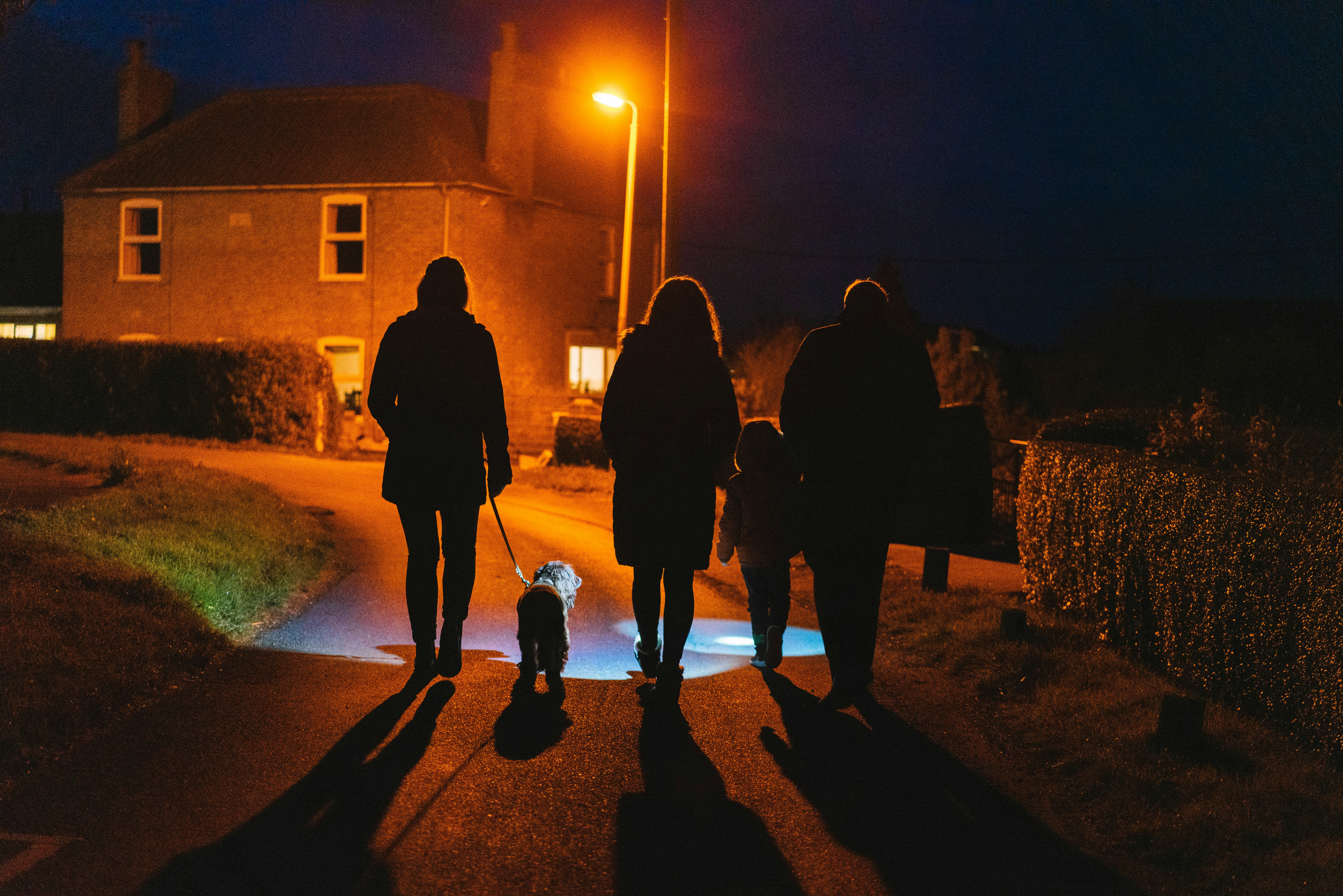 a group of people walking down a street at night