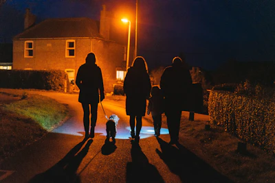 a group of people walking down a street at night
