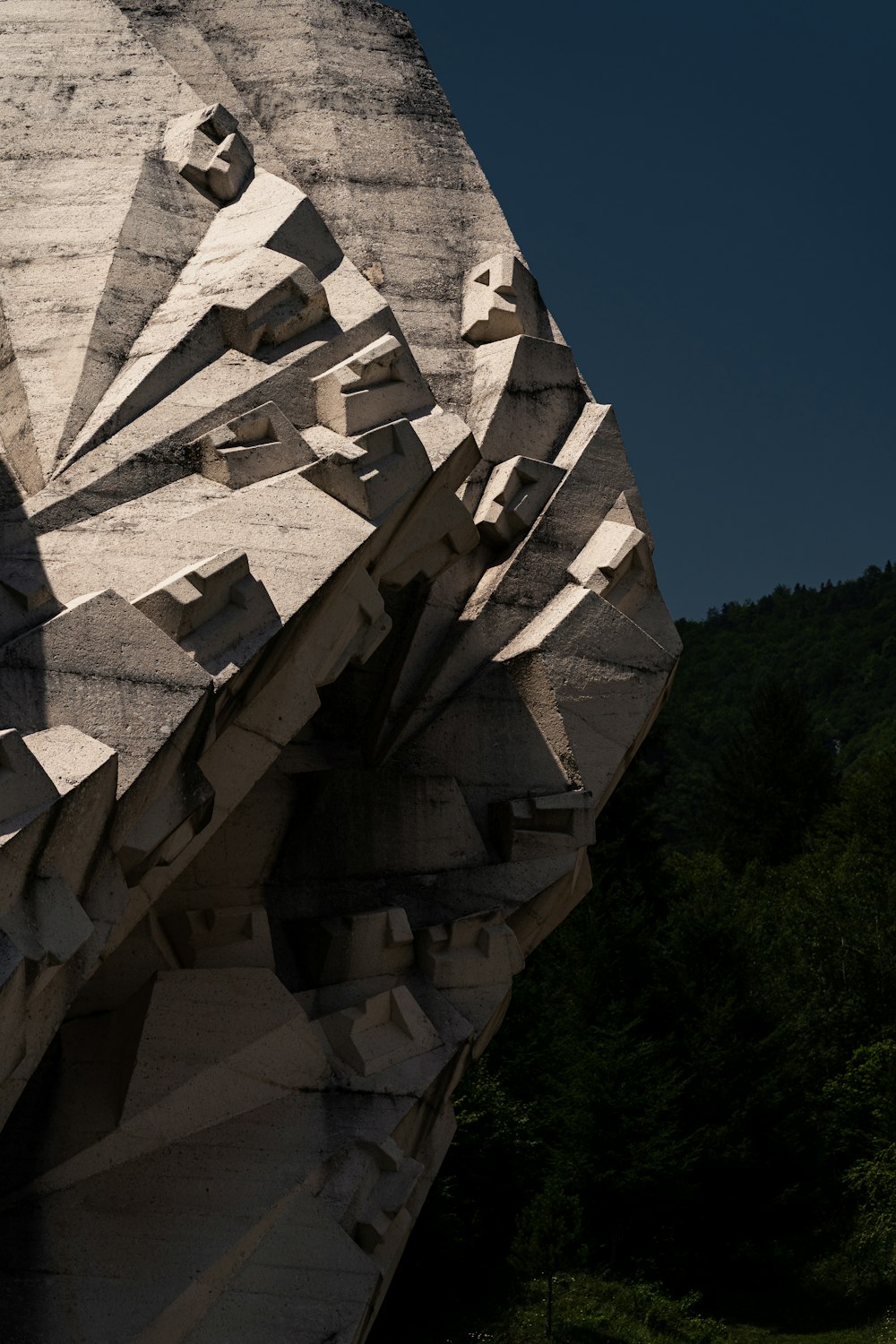 Eine Skulptur eines Gesichts wird vor blauem Himmel gezeigt