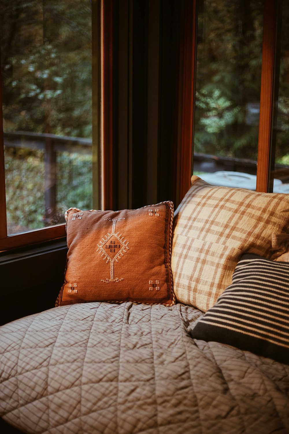 a bed with a quilt and pillows in front of a window