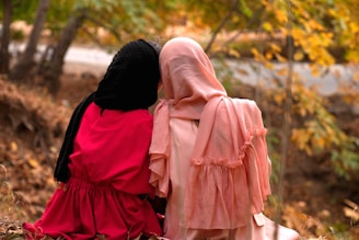 two women dressed in pink and black sitting on the ground
