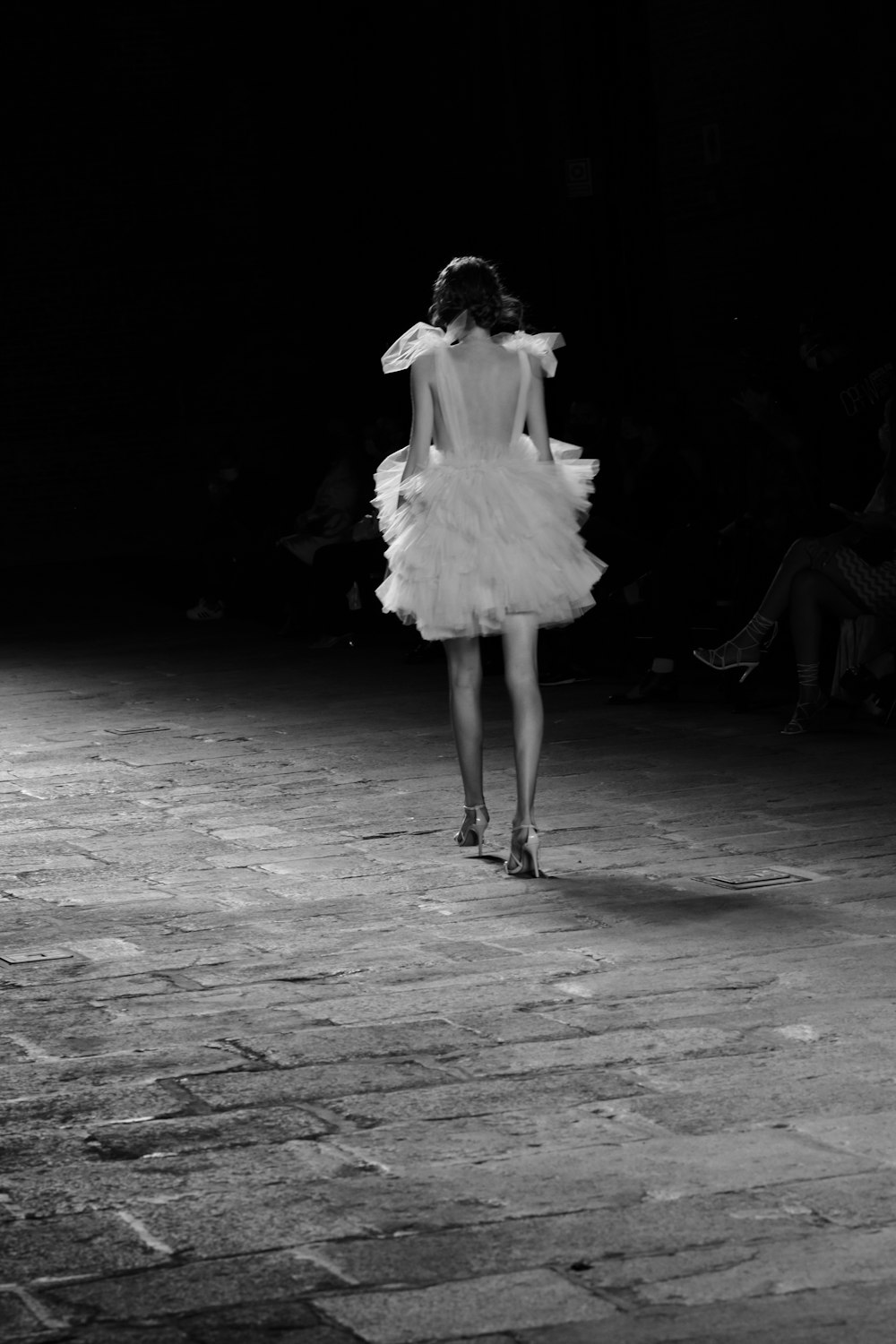 a woman in a white dress walking down a runway
