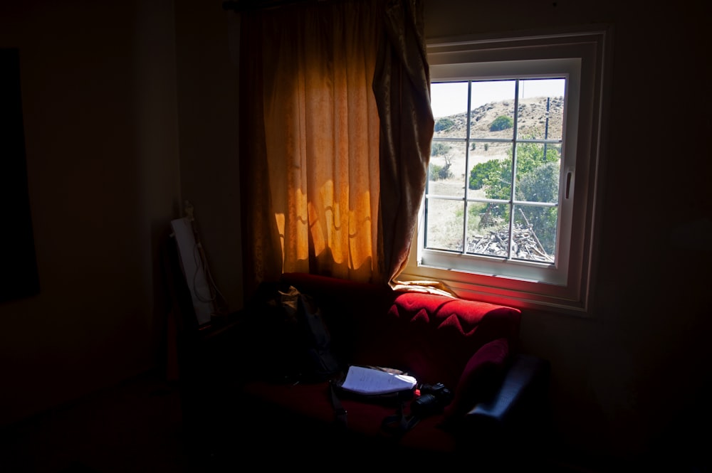 a red couch sitting in front of a window