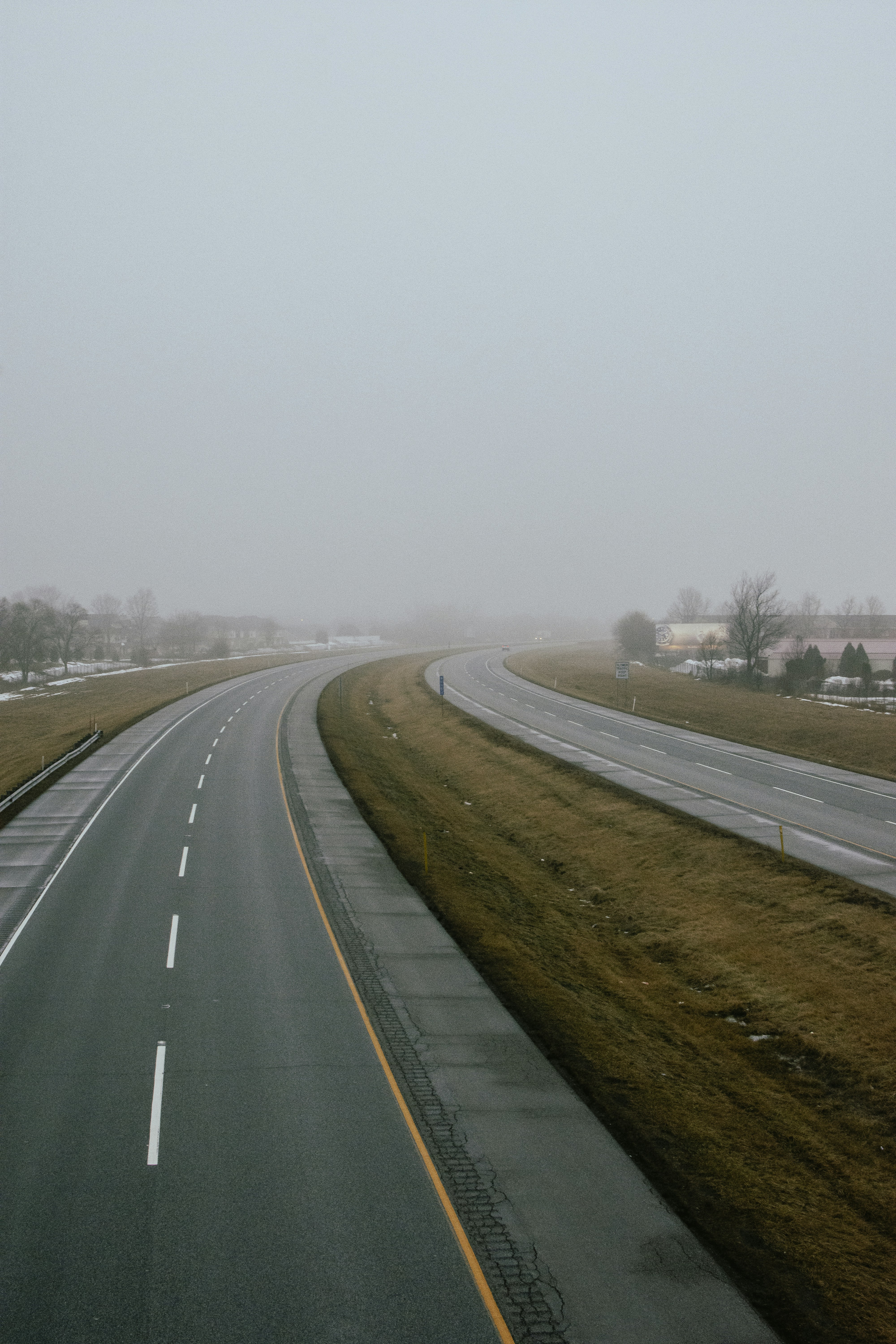 a foggy day on a highway with a car driving down the road