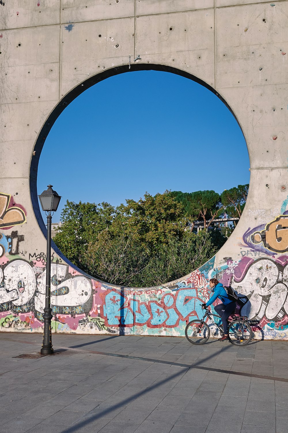 Un hombre montando en bicicleta más allá de una pared cubierta de graffiti