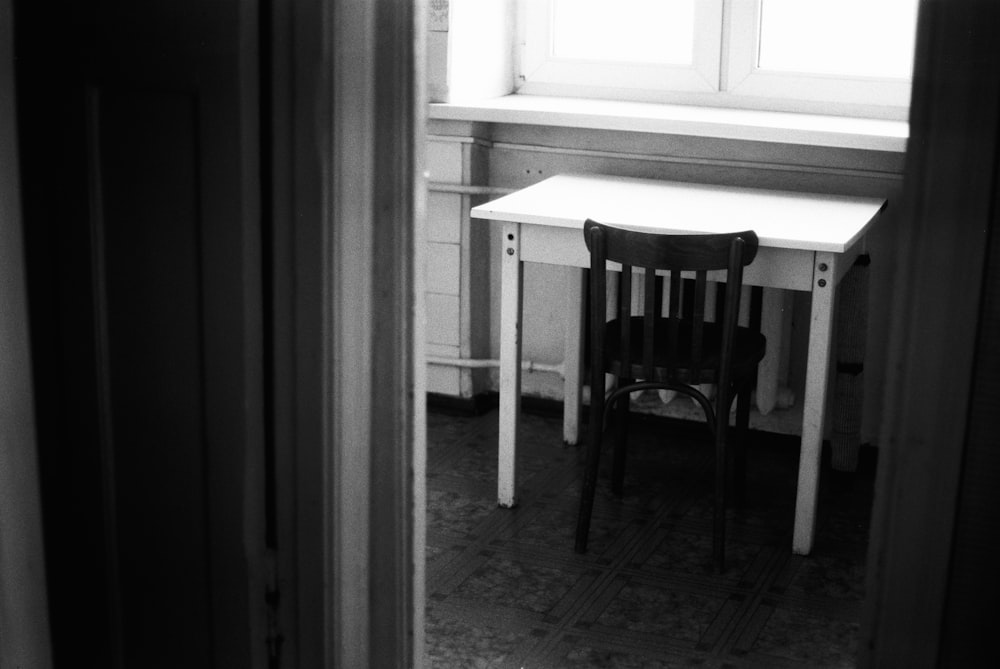 a black and white photo of a desk and chair