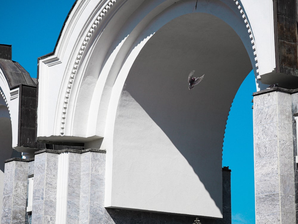 a white arch with a clock on the side of it