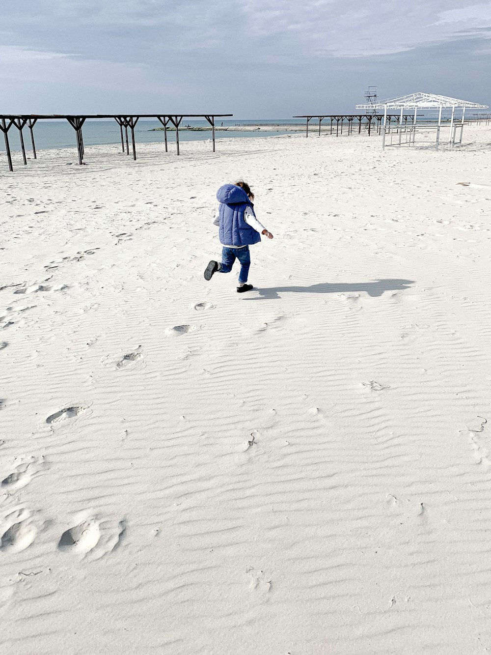 a woman walking across a snow covered beach