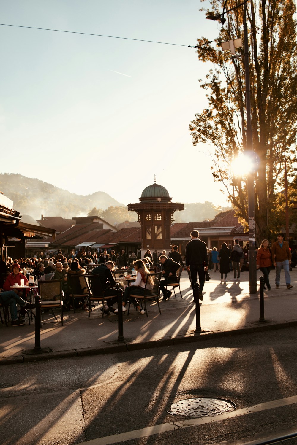 a group of people walking down a street next to a clock tower