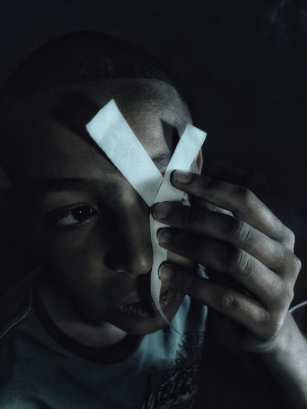 a young boy holding a piece of paper with tape on it