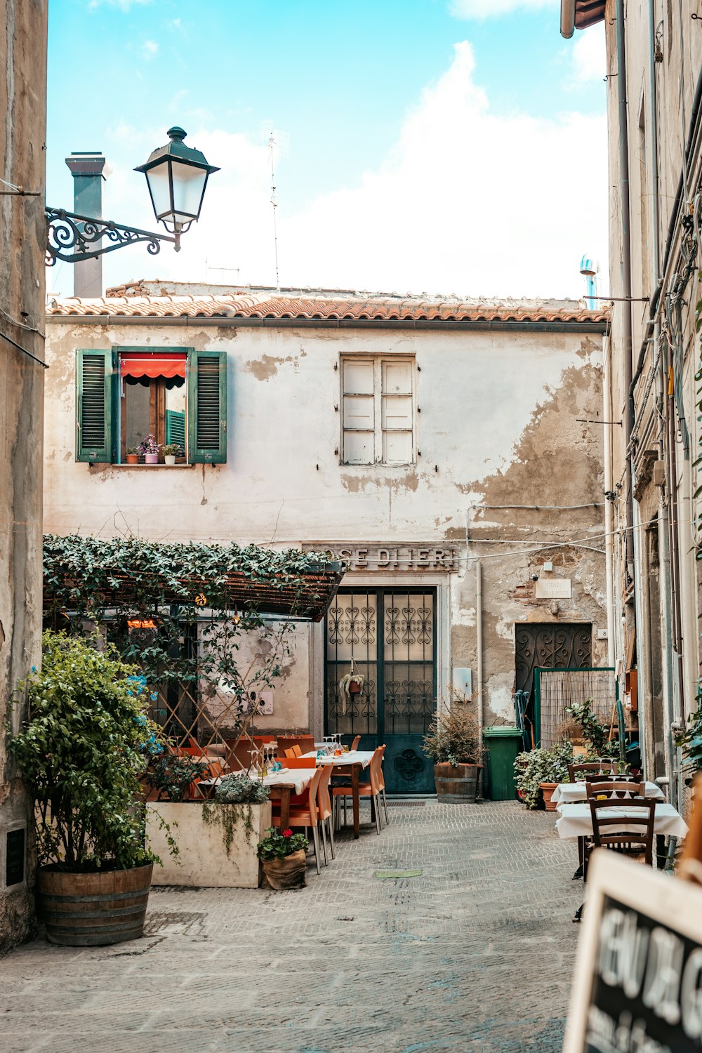 an alley way with tables and chairs in front of a building