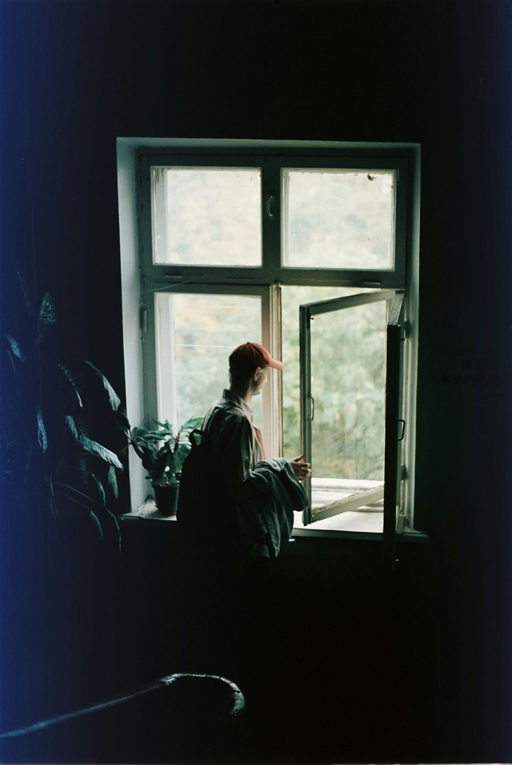 a person sitting on a window sill looking out the window