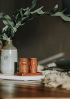 A close-up of a ceramic vase set with delicate floral patterns on a rustic table.