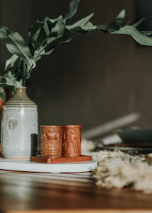 A close-up of a beautifully handcrafted ceramic vase with delicate floral patterns, sitting on a wooden table.