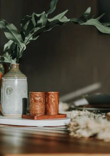 Handcrafted olive green ceramic vase on a wooden table with natural light