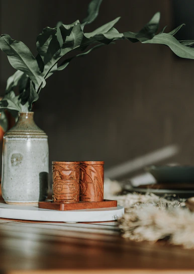 A close-up of a beautifully handcrafted ceramic vase with delicate floral patterns, sitting on a wooden table.