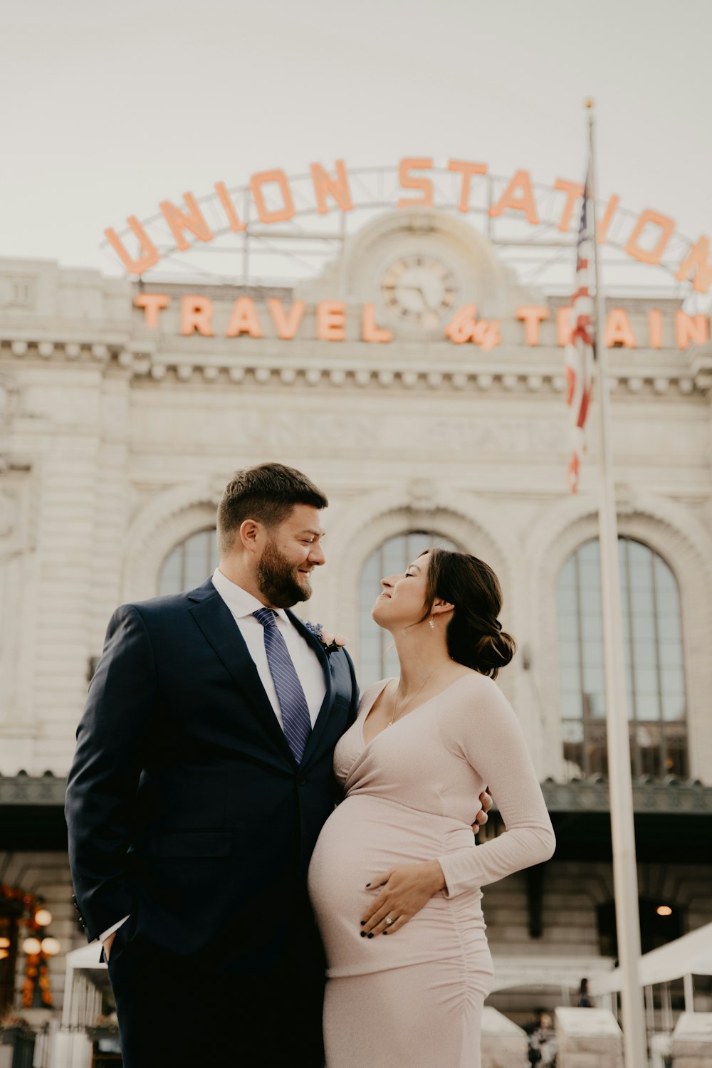 a pregnant couple standing in front of union station