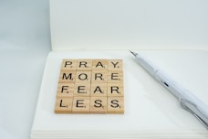 a wooden scrabble that says pray more fear less