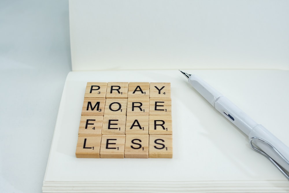 a wooden scrabble that says pray more fear less