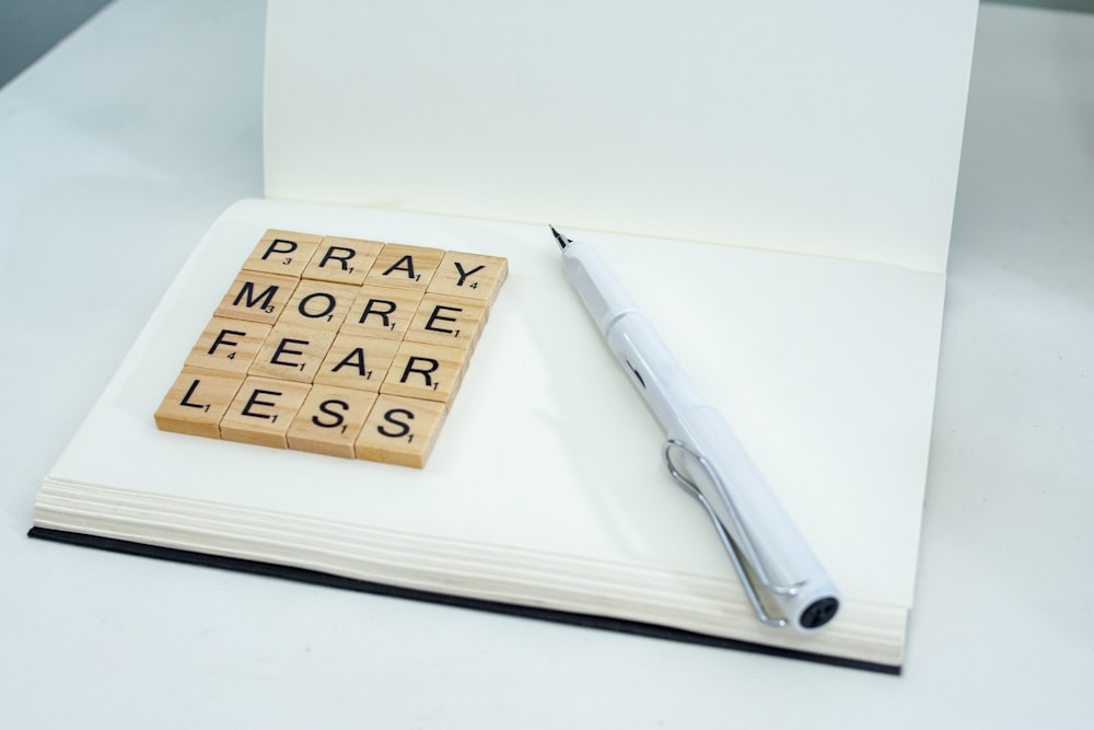 a notepad with scrabble letters and a pen on top of it