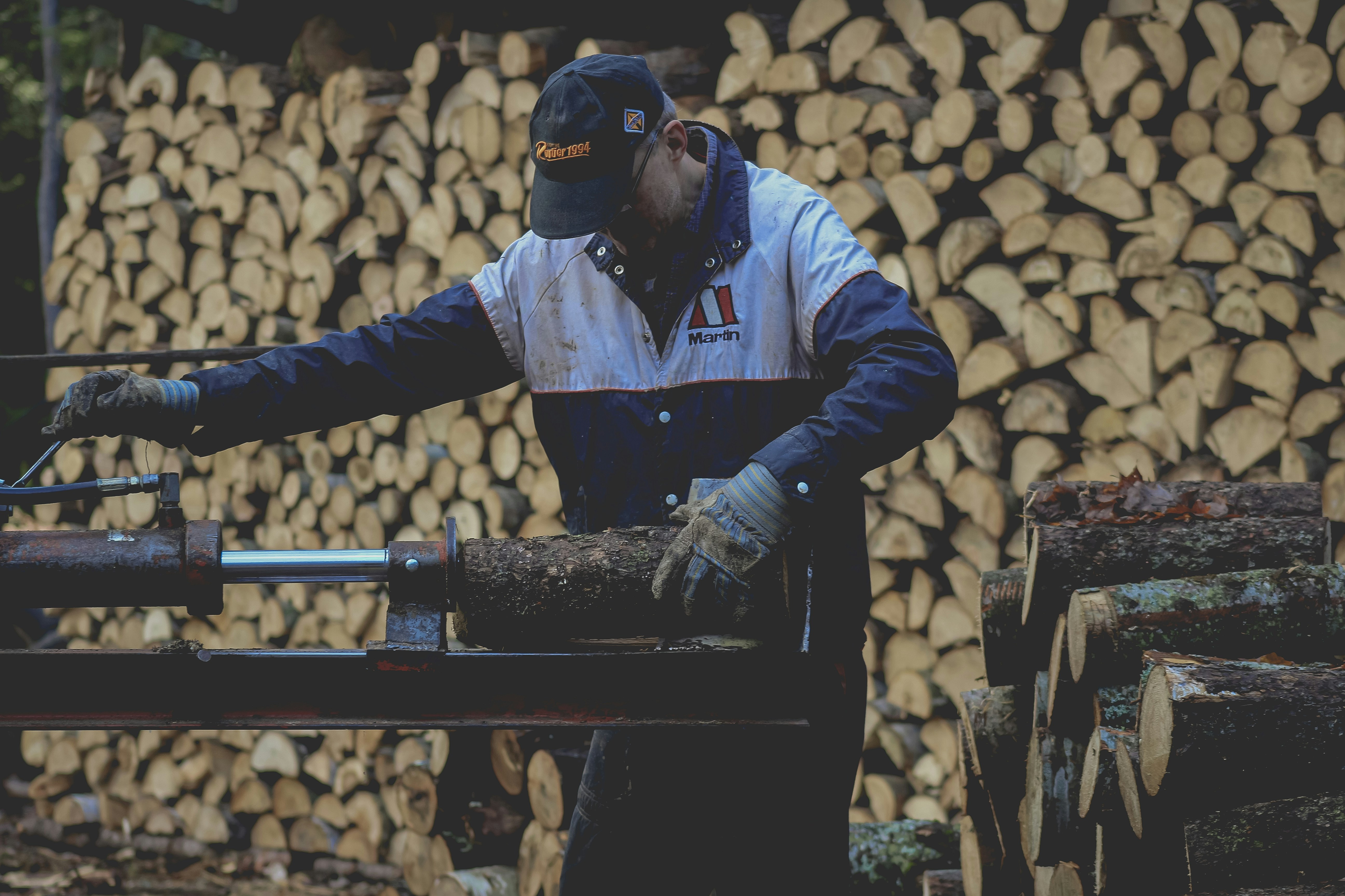 a man wearing a hat and gloves working on a piece of wood