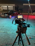 a camera set up on a tripod with a car in the background