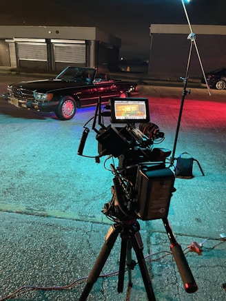 a camera set up on a tripod with a car in the background