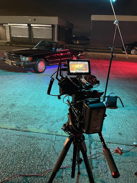 a camera set up on a tripod with a car in the background