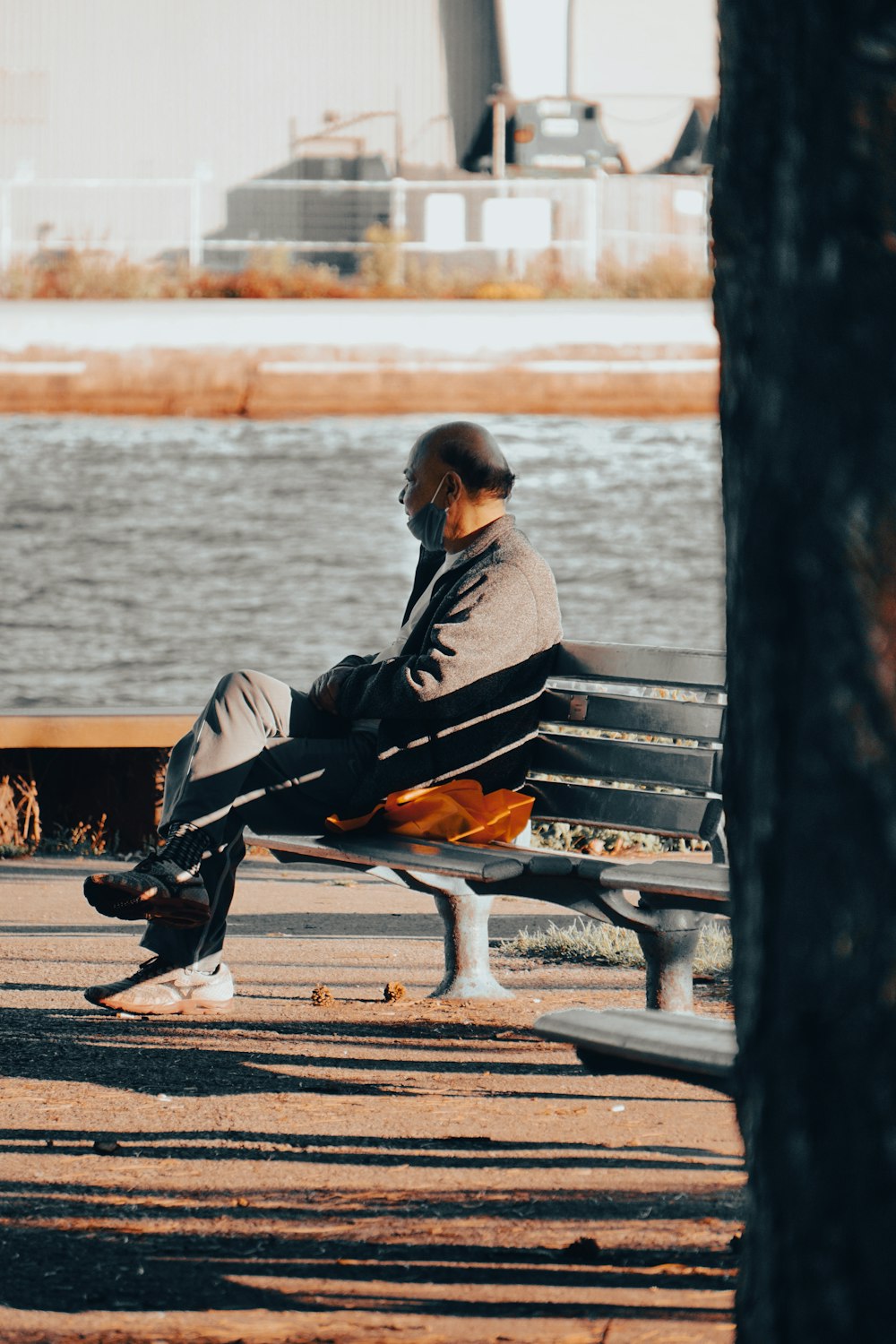 a man sitting on a bench next to a body of water