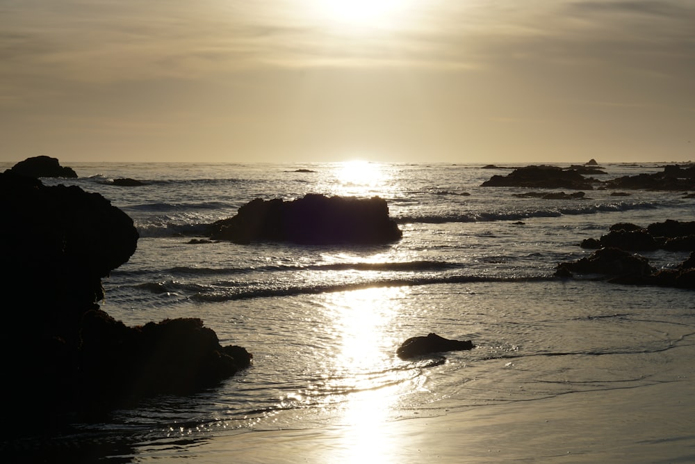 the sun is setting over the water at the beach