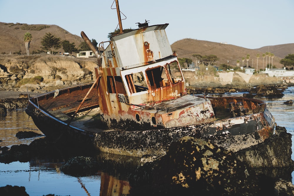a rusted boat sitting on top of a body of water