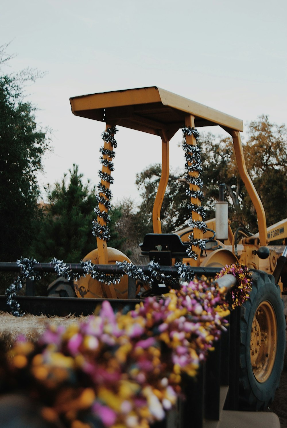 a yellow tractor parked next to a bunch of purple flowers