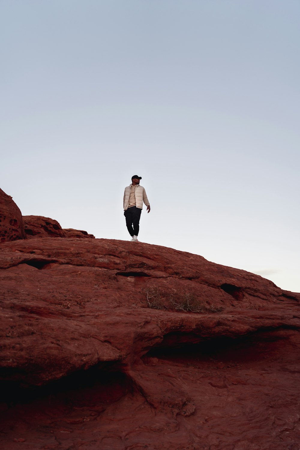 a man standing on top of a red rock