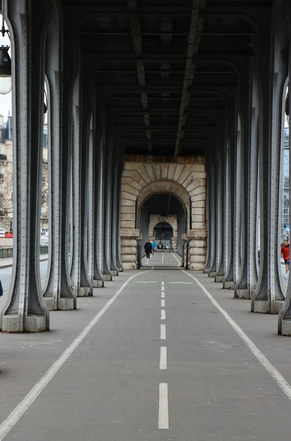 a person riding a bike down a street under a bridge