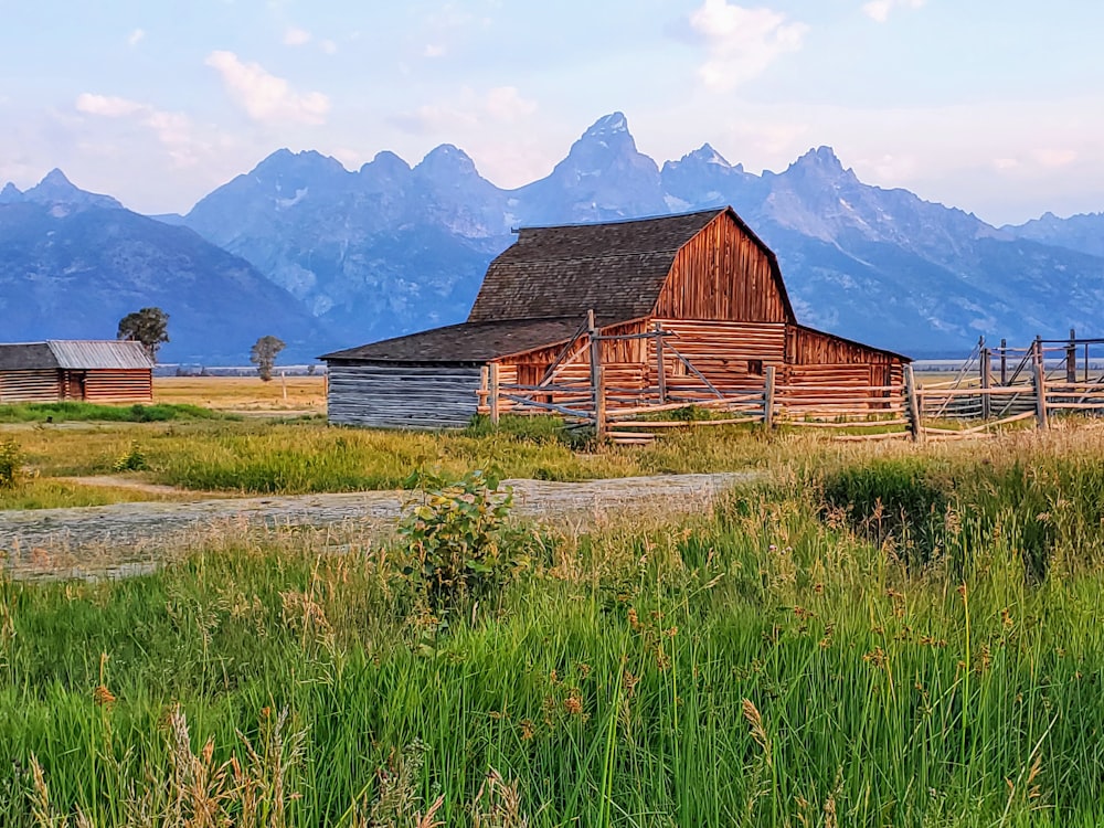 a barn in a field with mountains in the background