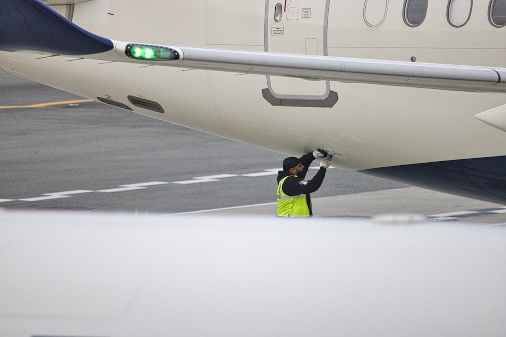a man in a safety vest standing next to an airplane