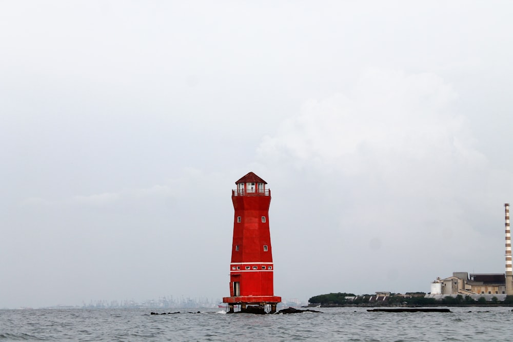 a red light house in the middle of the ocean
