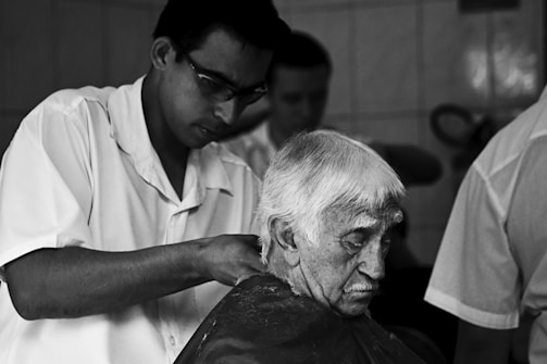 a black and white photo of a man getting his hair cut