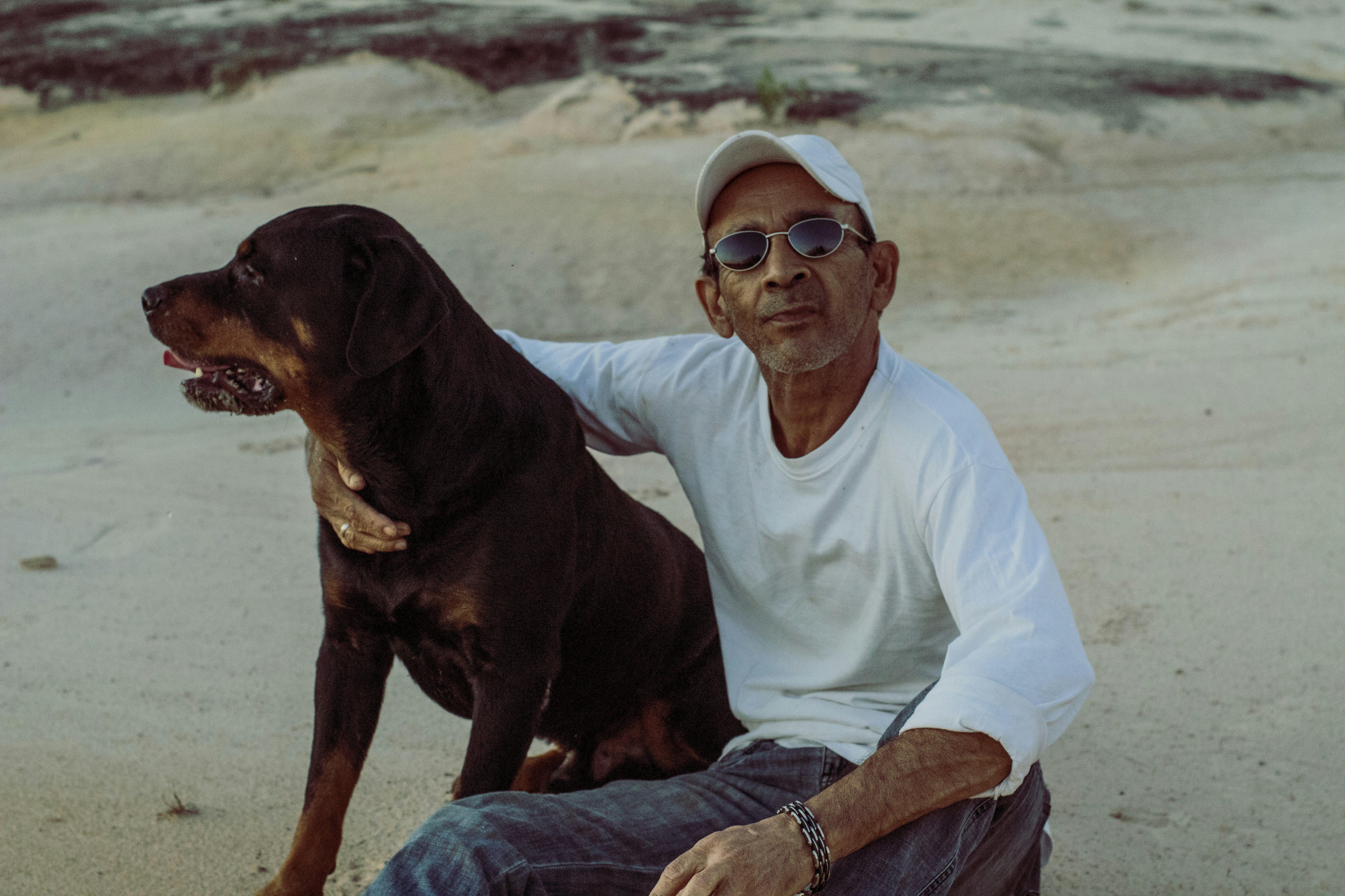 A man sitting on a beach with a dog photo – Free Brasil Image on Unsplash