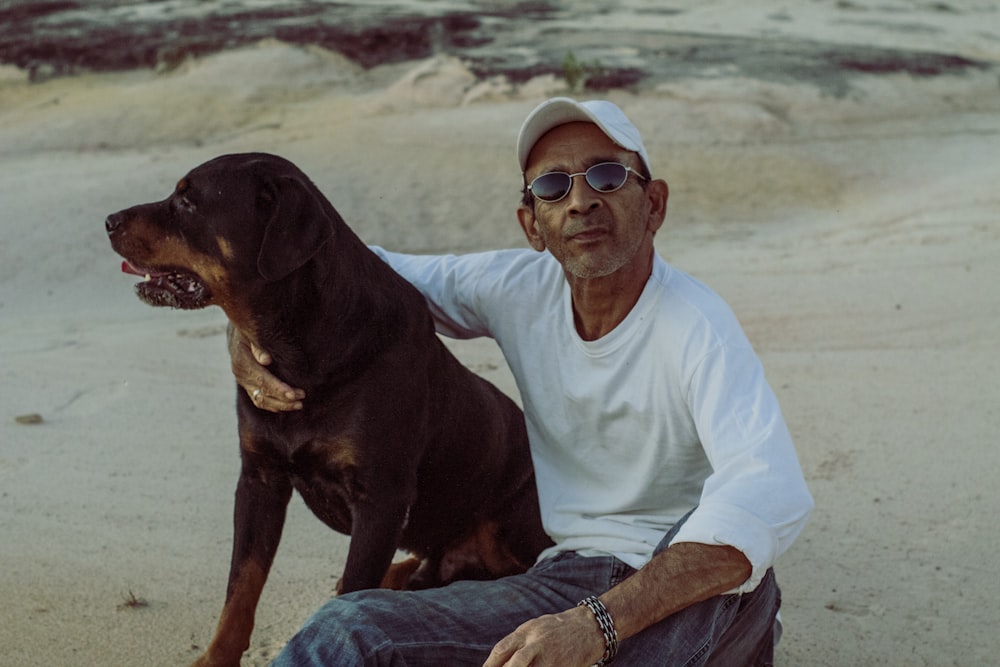 a man sitting on a beach with a dog