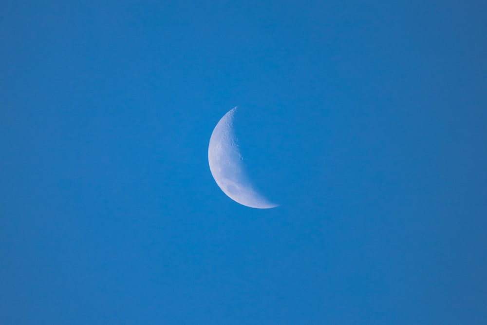 a half moon in a clear blue sky