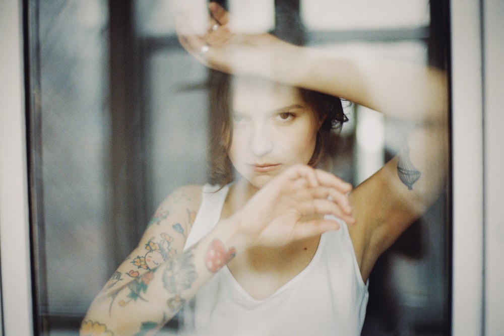 a woman with tattoos standing in front of a window