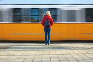 a woman in a red jacket is waiting for a train