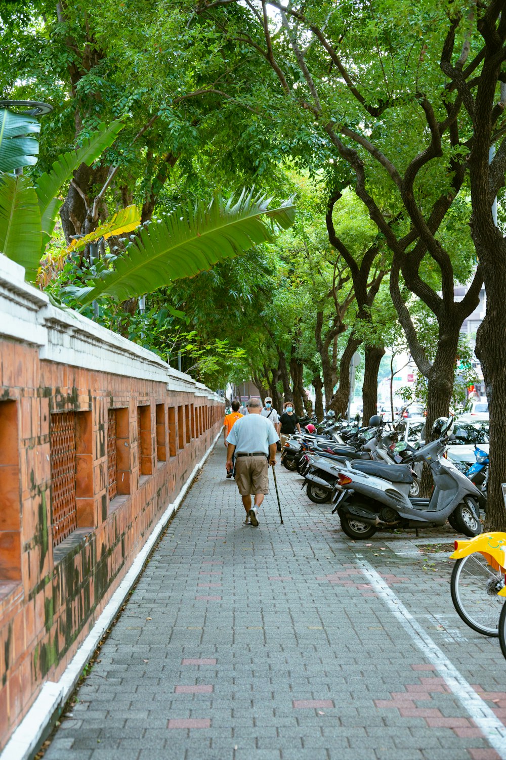 a man walking down a sidewalk next to a row of parked motorcycles