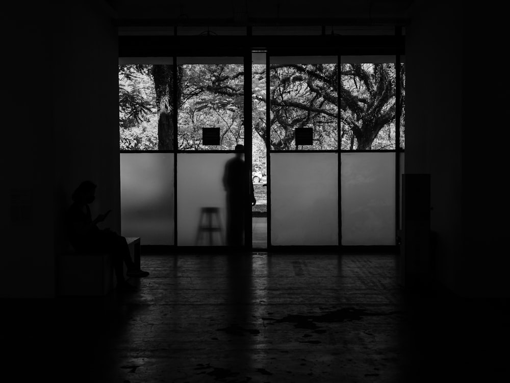 a black and white photo of a person sitting in front of a window