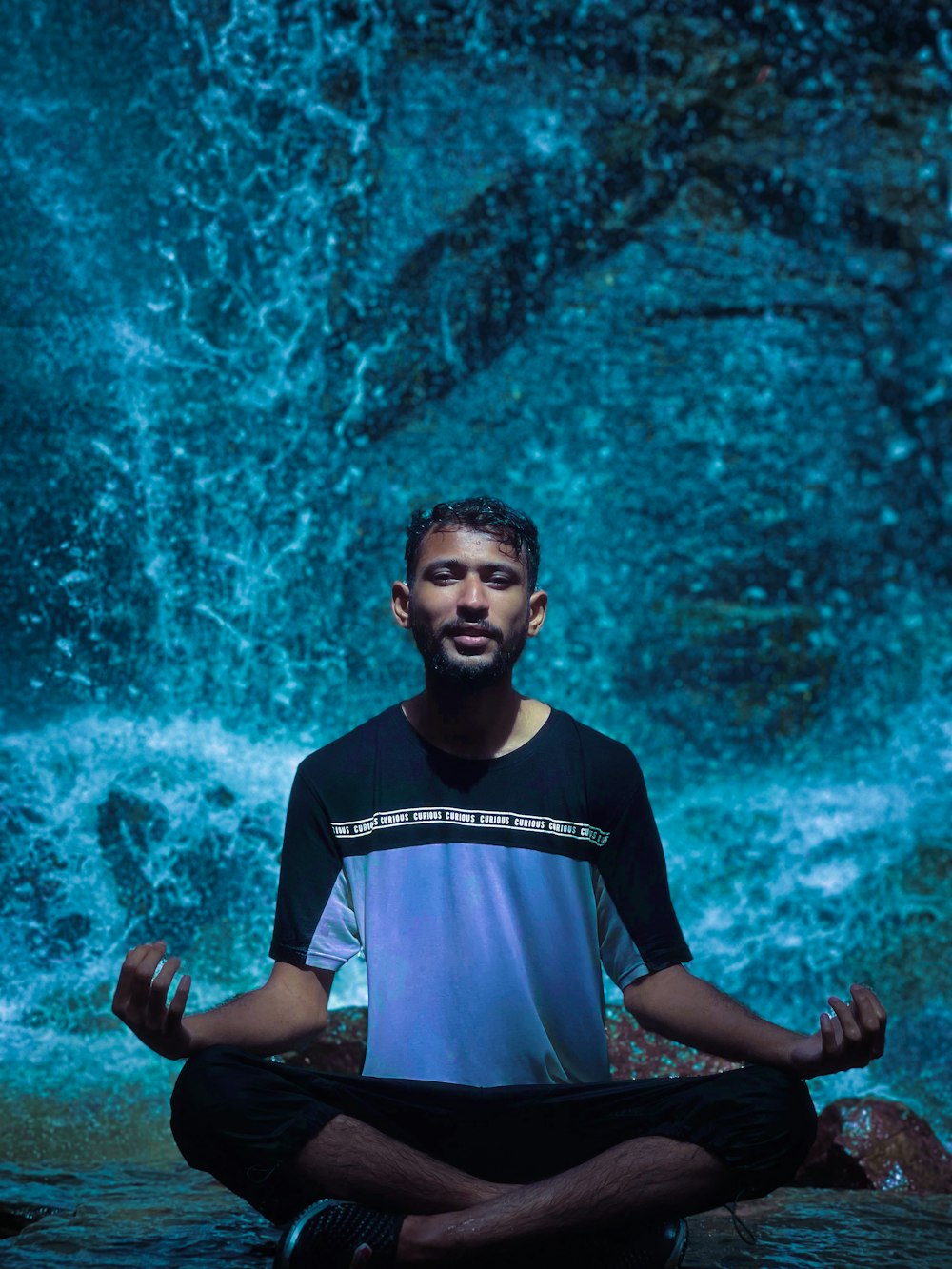 a man meditating in front of a waterfall